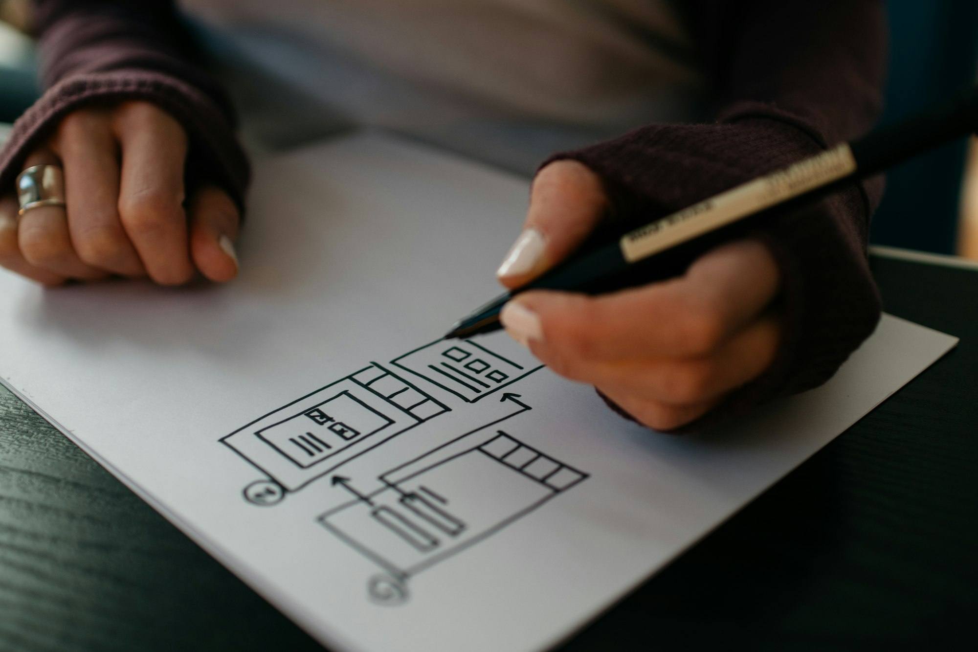 Hand zeichnet mit Stift Seitenentwürfe auf weißes Papier